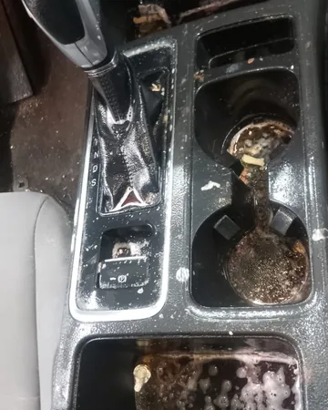 Center console cup holders full of spilled, dried drinks